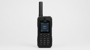 Front-facing rugged black satellite phone with long antenna, numeric keypad, and small display screen showing ‘Iridium Registered,’ placed on a plain light gray background in a clean studio product shot.